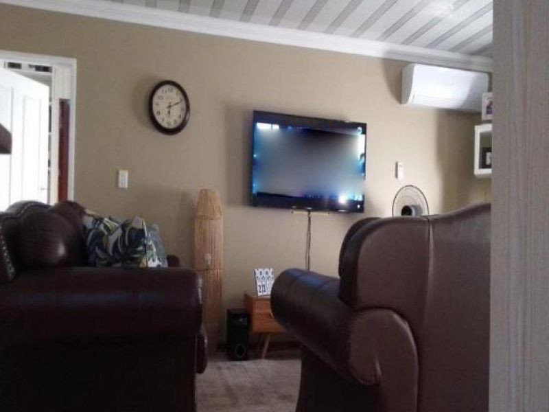 A comfortable living room featuring a wall-mounted air conditioning unit and crown molding, providing a functional and relaxed space.