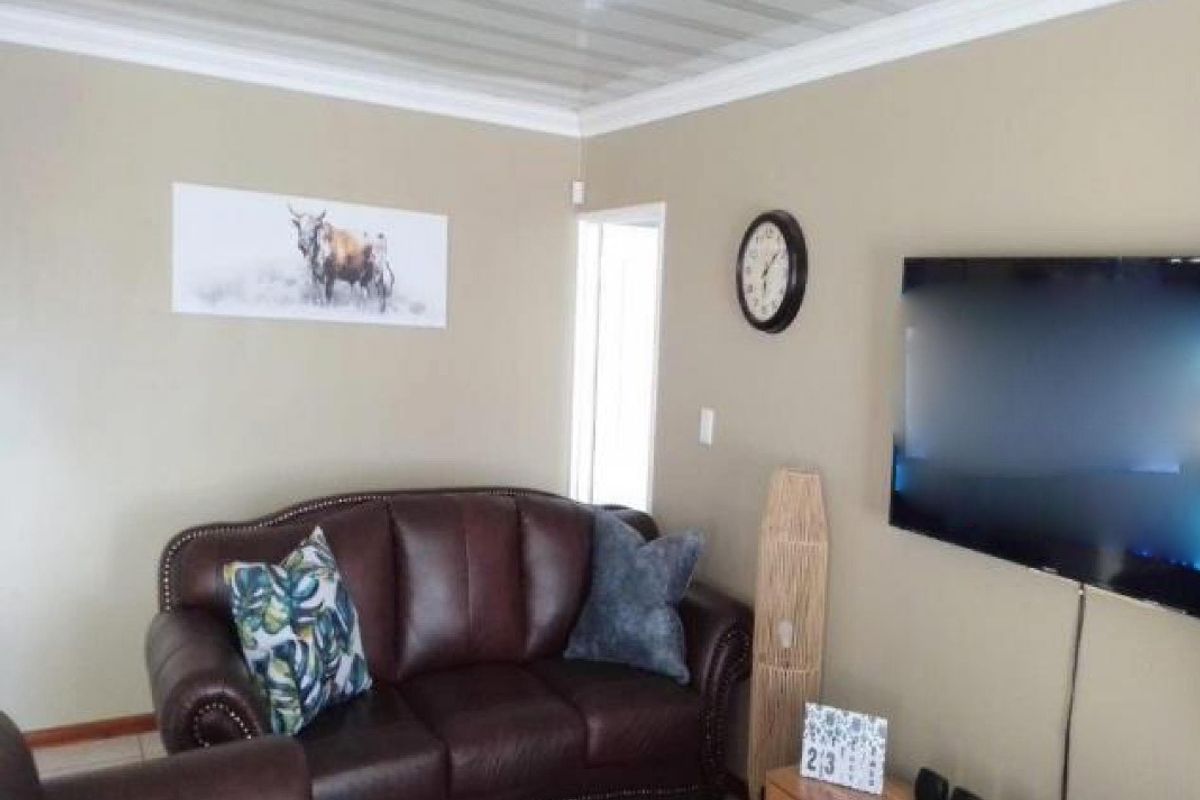 A comfortable living room featuring neutral wall tones, crown molding, and a clean, functional layout suitable for relaxation.