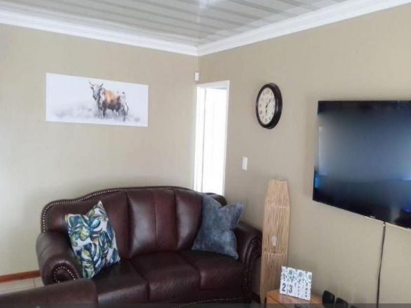 A comfortable living room featuring neutral wall tones, crown molding, and a clean, functional layout suitable for relaxation.