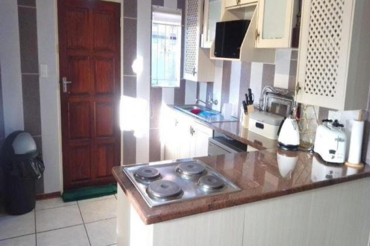 A functional kitchen featuring granite countertops, a built-in electric hob, and ample cabinetry, providing a practical workspace for daily meal preparation.