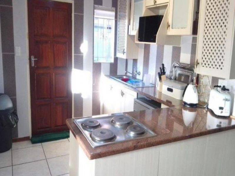A functional kitchen featuring granite countertops, a built-in electric hob, and ample cabinetry, providing a practical workspace for daily meal preparation.