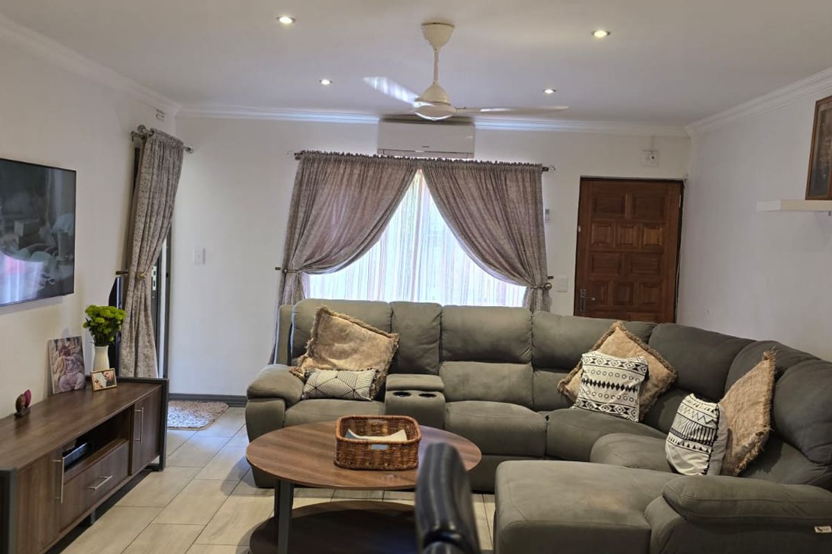 A comfortable living room featuring tiled flooring, recessed ceiling lighting, a ceiling fan, and a wall-mounted air conditioning unit.