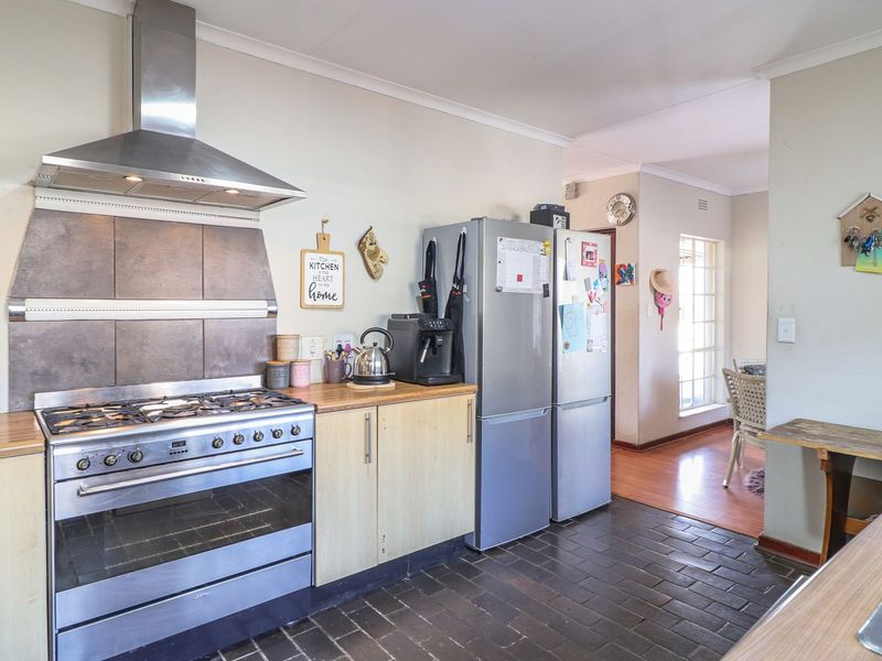 Functional kitchen featuring a gas stove, stainless steel extractor fan, laminate countertops, and durable brick flooring, with an adjacent dining area.