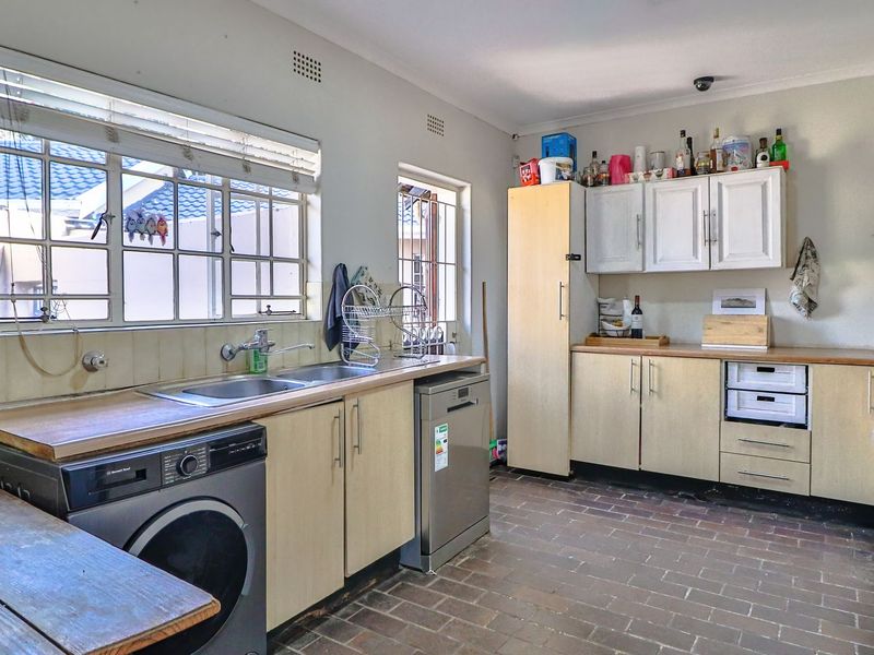 Functional kitchen featuring laminate countertops, built-in cabinetry, a double sink, and a built-in hob with extractor fan, finished with durable tiled flooring.