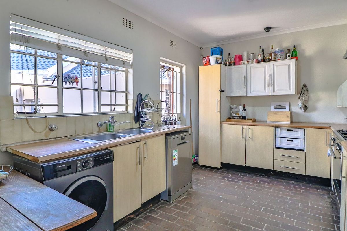 Functional kitchen featuring laminate countertops, built-in cabinetry, a double sink, and a built-in hob with extractor fan, finished with durable tiled flooring.