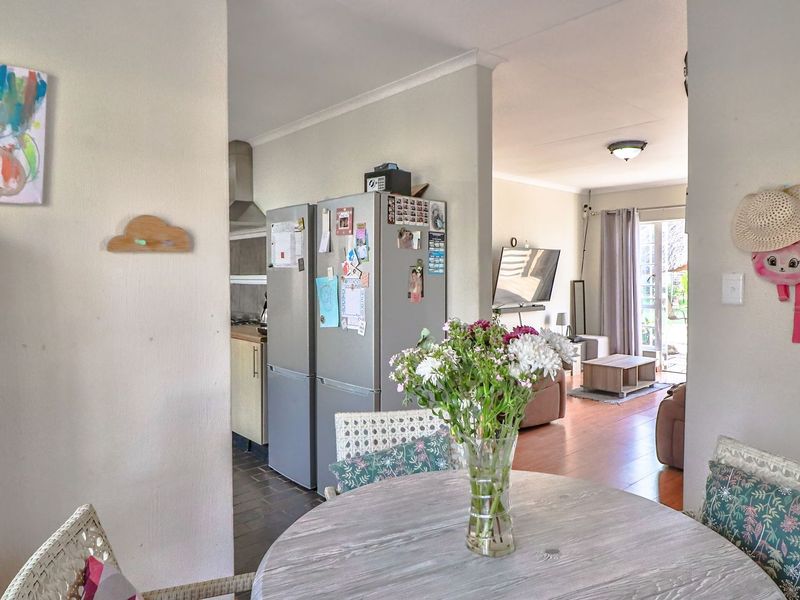 Open plan living area featuring a kitchen with built-in cabinetry and extractor fan, flowing into a lounge with access to the outdoor space.