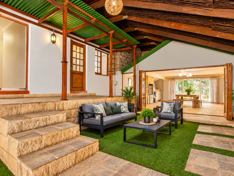 A spacious covered patio featuring exposed timber rafters, stone steps, and bi-fold doors that provide seamless access to the interior living area.