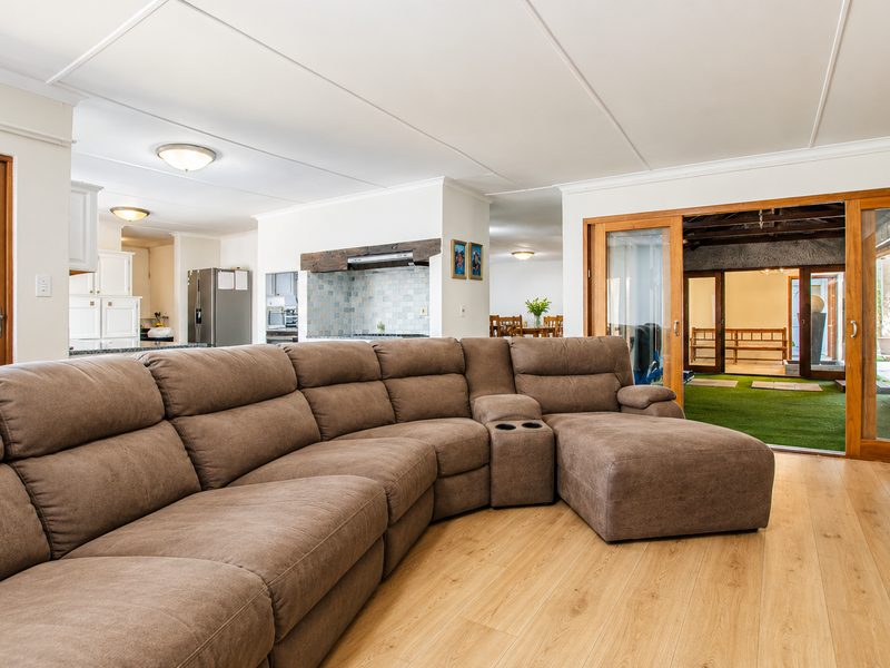 Spacious open-plan living area featuring laminate flooring, recessed lighting, and large sliding glass doors providing seamless access to the outdoor patio area.