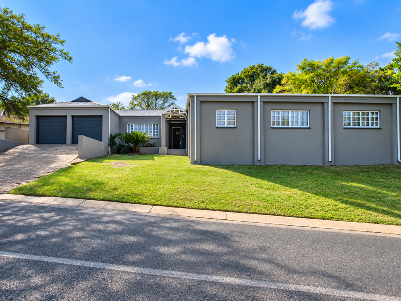 Front elevation of a modern single-story house featuring a double garage, paved driveway, and well-maintained lawn.