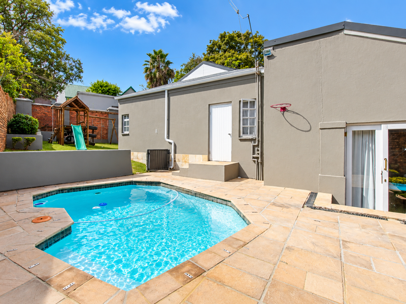 Outdoor pool area featuring stone paving, a swimming pool, and a brick boundary wall, providing a functional space for recreation and relaxation.