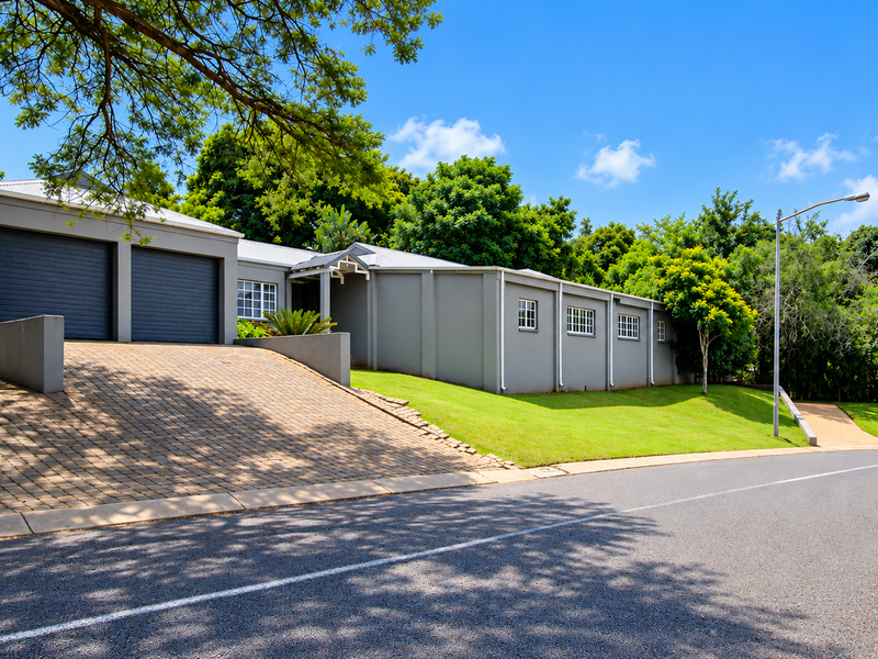 Front view of a modern house featuring a double garage, paved driveway, and well-maintained lawn in a quiet residential setting.