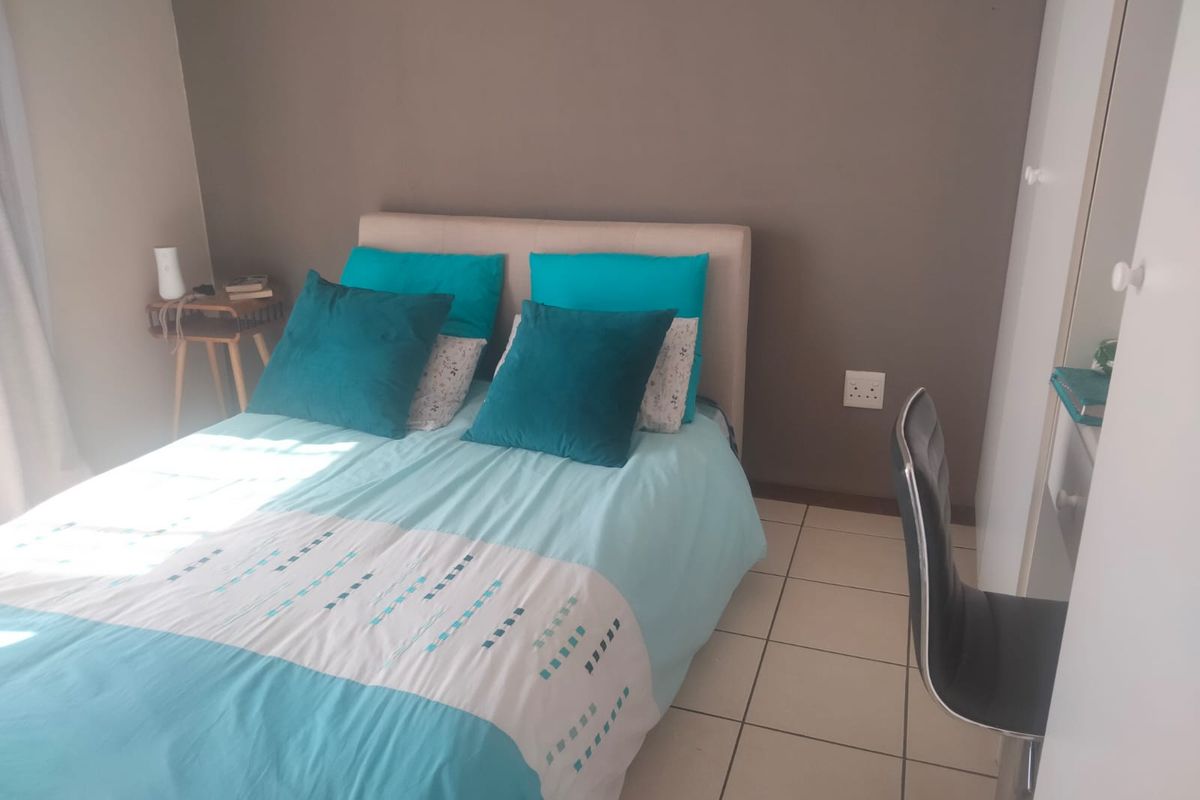 A bedroom featuring tiled flooring and a built-in wardrobe with white doors.