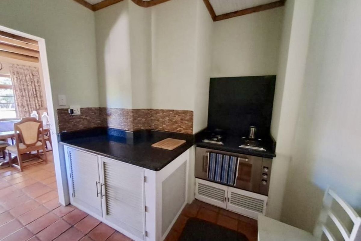 A compact kitchen area featuring built-in cabinetry, a dark stone countertop, and a fitted stove with an integrated oven.