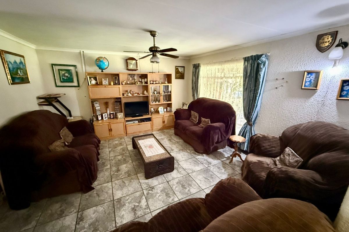 A living room featuring tiled flooring, a ceiling fan, and textured wall finishes, offering a functional space ready for modern updates.