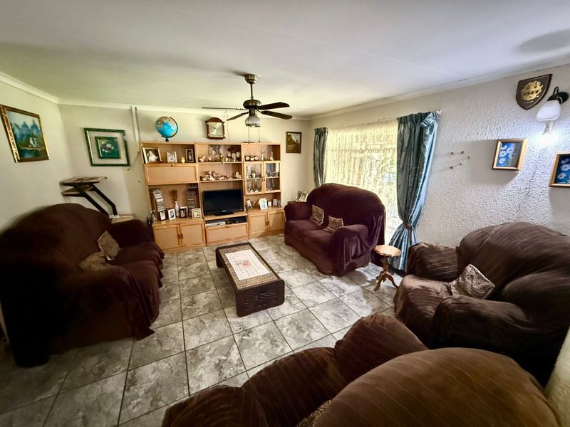 A living room featuring tiled flooring, a ceiling fan, and textured wall finishes, offering a functional space ready for modern updates.