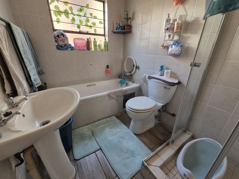 A functional bathroom featuring a pedestal basin, bathtub, toilet, and a separate shower enclosure with tiled walls.