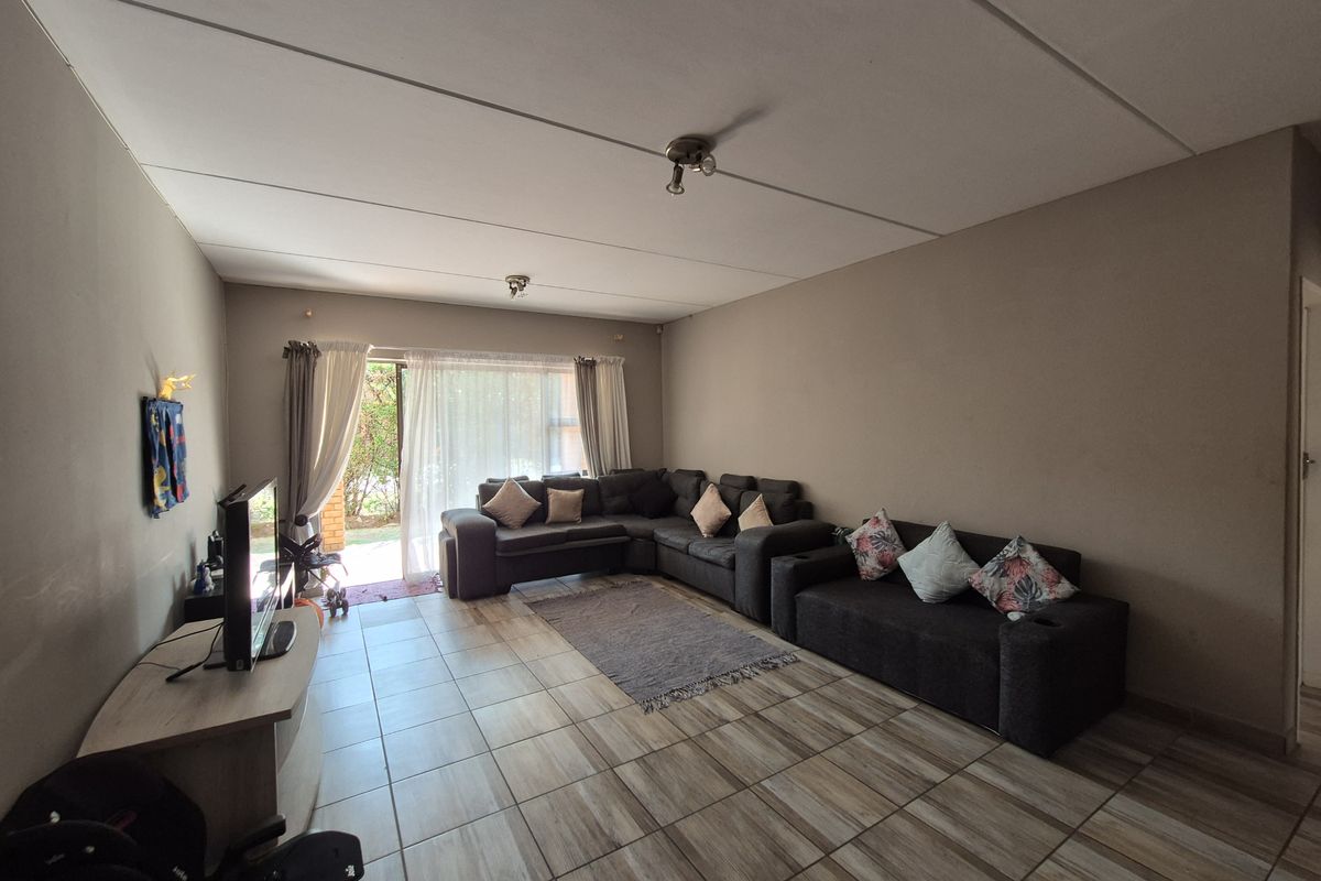 Spacious living room featuring tiled flooring and a sliding glass door providing access to the outdoor area.