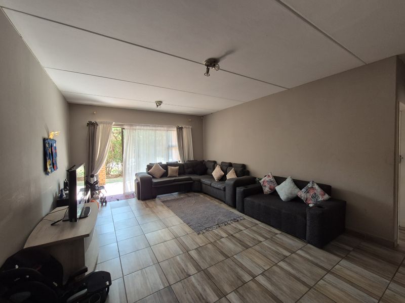 Spacious living room featuring tiled flooring and a sliding glass door providing access to the outdoor area.