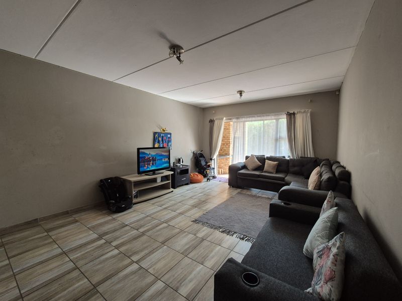 Spacious living room featuring tiled flooring and a sliding glass door providing access to the outdoor area.