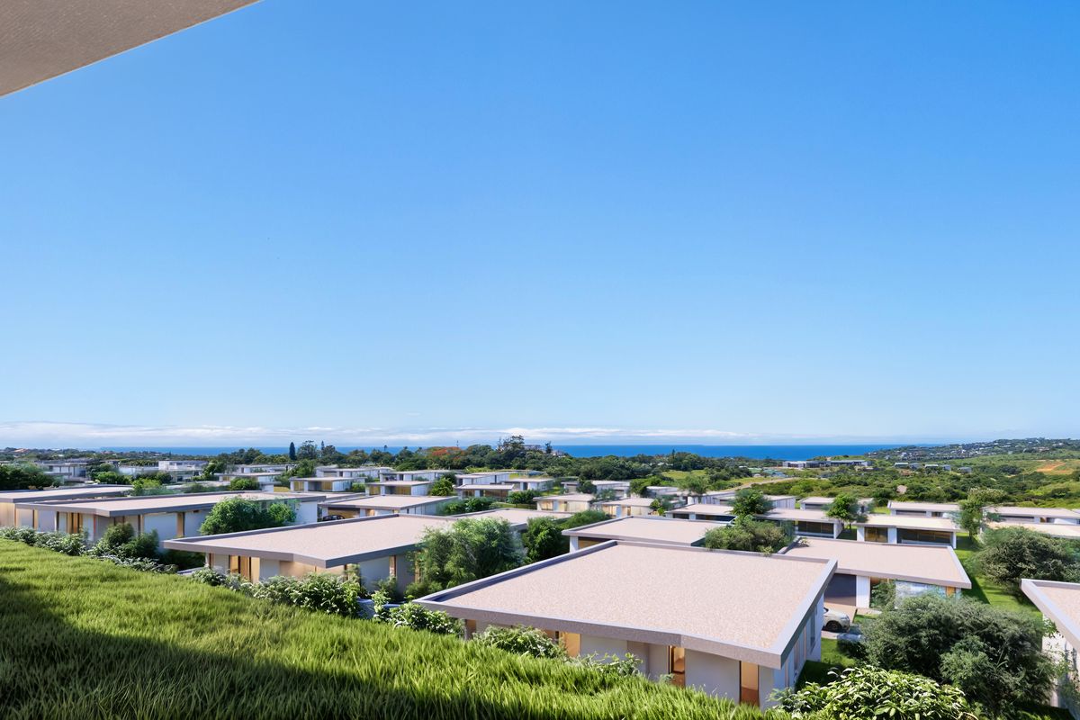 An elevated aerial view showcasing a modern residential estate development with landscaped surroundings and distant coastal views.