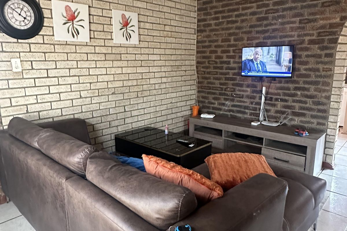 Living room featuring exposed brick feature walls, tiled flooring, and a ceiling fan.