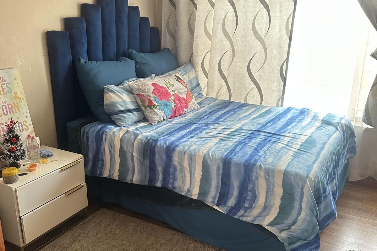 A bedroom featuring wood-look flooring and a large window with curtains, providing natural light to the space.