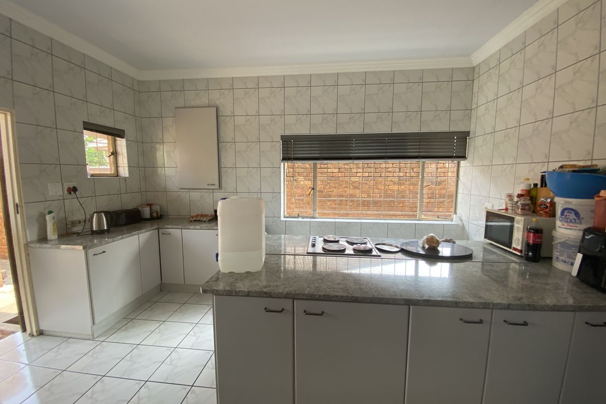 A functional kitchen featuring granite countertops, built-in cabinetry, a fitted hob, and tiled flooring with wall-to-wall tiling.