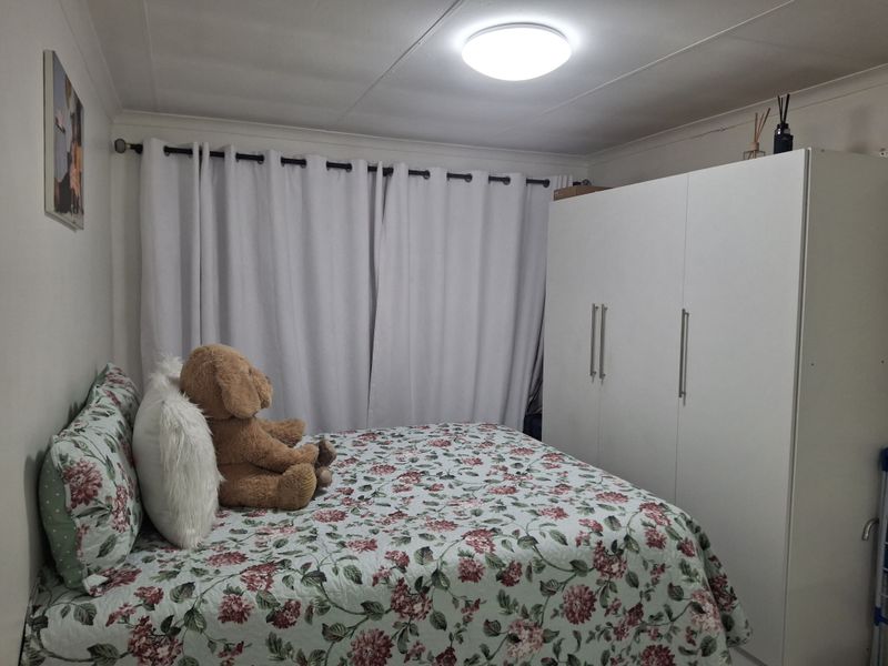 A functional bedroom featuring a built-in wardrobe, ceiling lighting, and window treatments, providing a comfortable and practical living space.