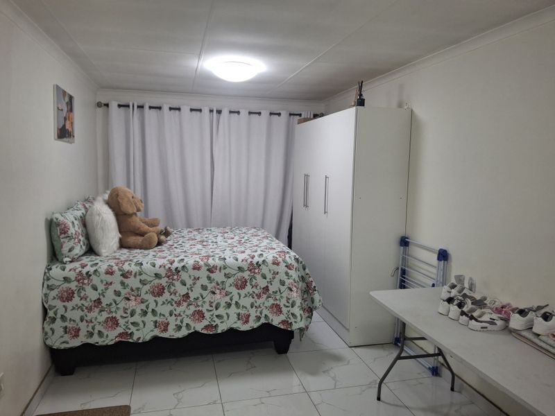 A functional bedroom featuring tiled flooring, a built-in wardrobe, and neutral wall finishes, providing a clean and practical living space.