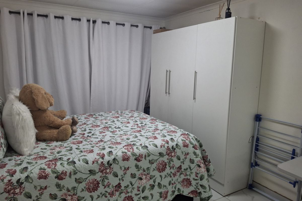 A functional bedroom featuring tiled flooring, a built-in wardrobe, and neutral wall finishes, providing a clean and practical living space.