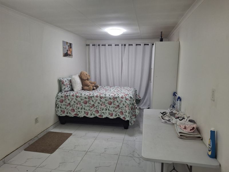 A functional bedroom featuring tiled flooring, a central ceiling light, and window curtains, providing a neutral base for personalization.