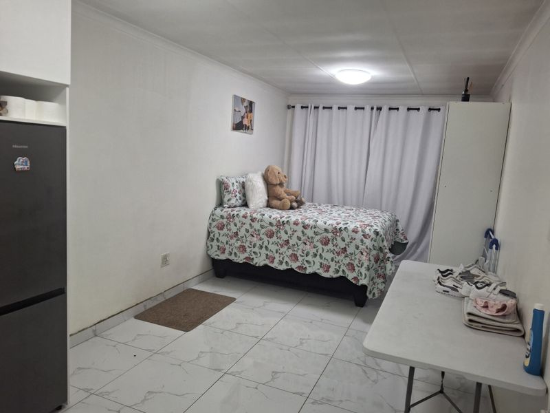 A functional bedroom featuring tiled flooring, a built-in cupboard, and neutral wall finishes, providing a clean and simple living space.