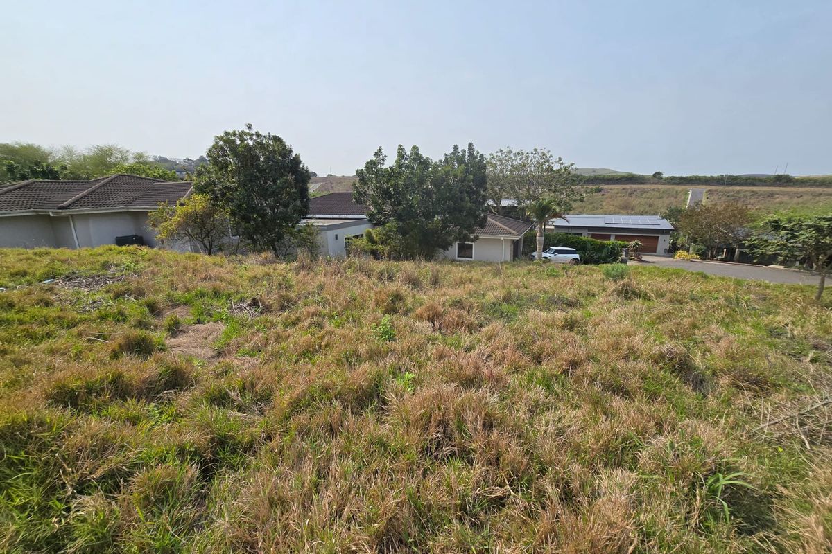 A view of an undeveloped residential plot of land with surrounding established neighborhood homes visible in the background.