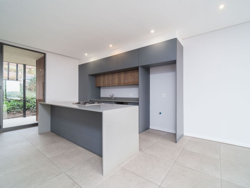 Modern kitchen featuring a central island with a gas hob, sleek grey cabinetry, tiled flooring, and direct access to an outdoor patio area.
