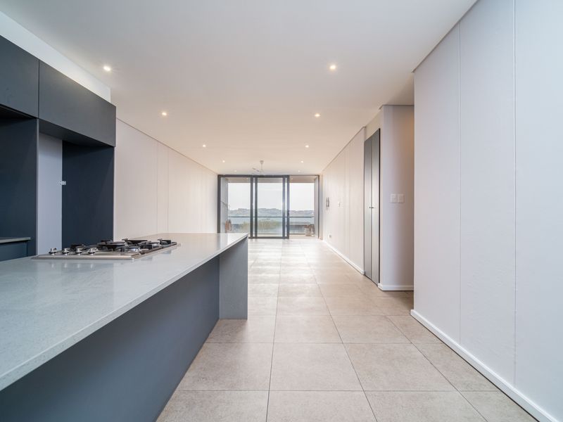 Modern open-plan living area featuring a sleek kitchen with stone countertops, gas hob, and large sliding doors leading to an outdoor space.