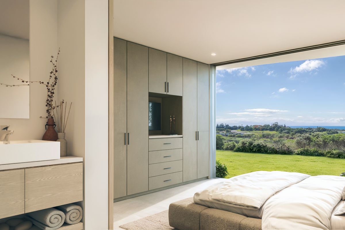 Modern bedroom featuring built-in cabinetry, an integrated vanity area, and large sliding glass doors opening to a scenic landscape view.