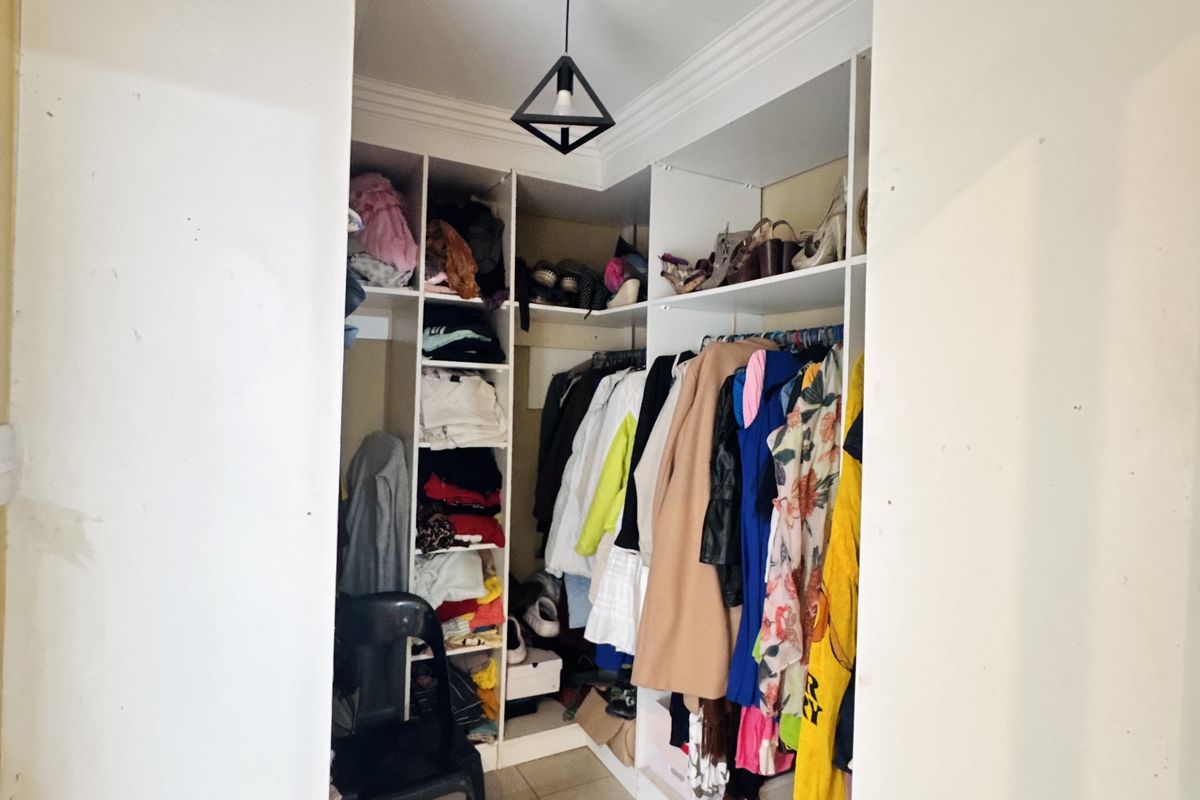 A walk-in closet featuring built-in shelving, hanging rails, and tiled flooring, providing organized storage space.