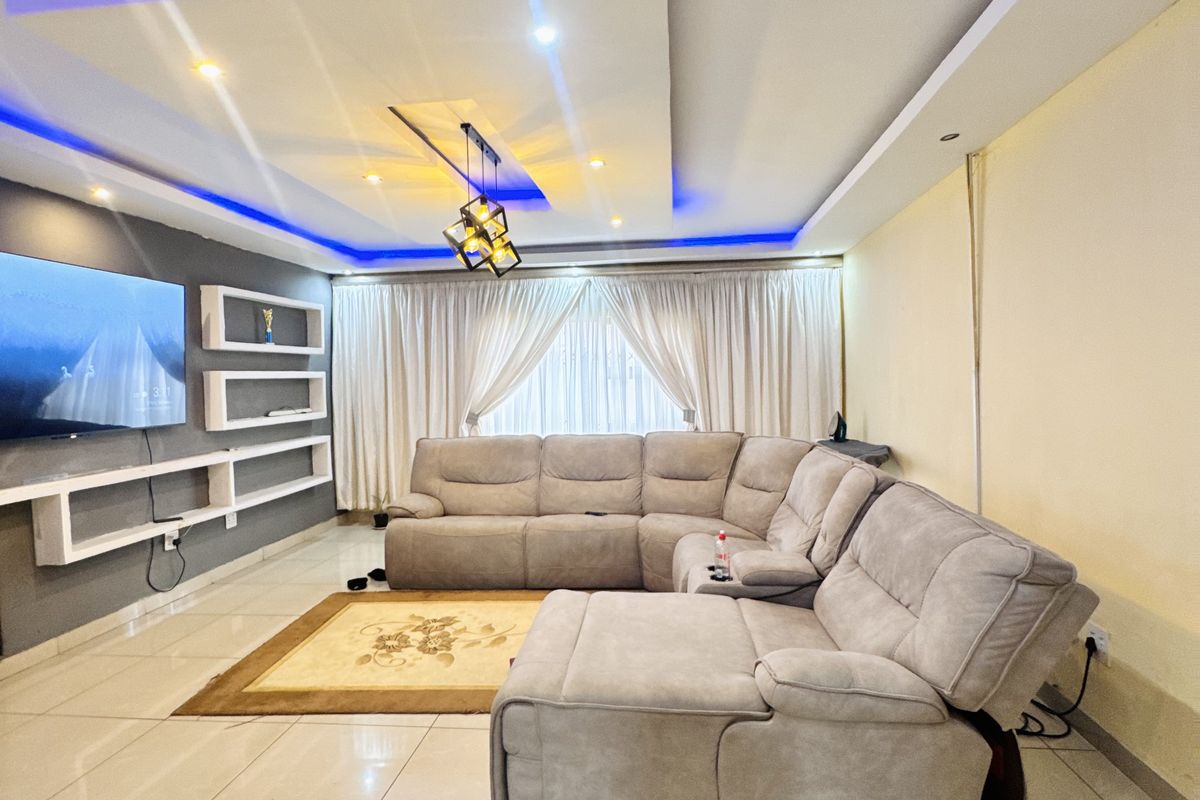 Modern living room featuring a recessed tray ceiling with integrated LED lighting, tiled flooring, and built-in wall shelving units.