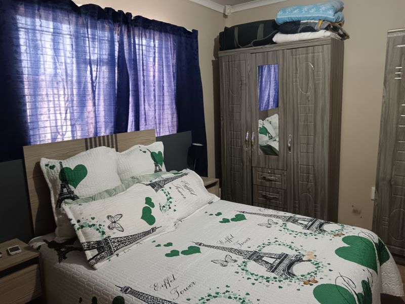 A functional bedroom featuring a built-in wardrobe and window with curtaining, providing a comfortable and practical living space.