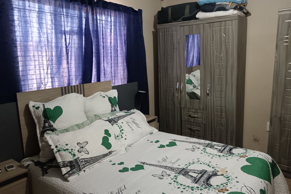 A functional bedroom featuring a built-in wardrobe and window with curtaining, providing a comfortable and practical living space.