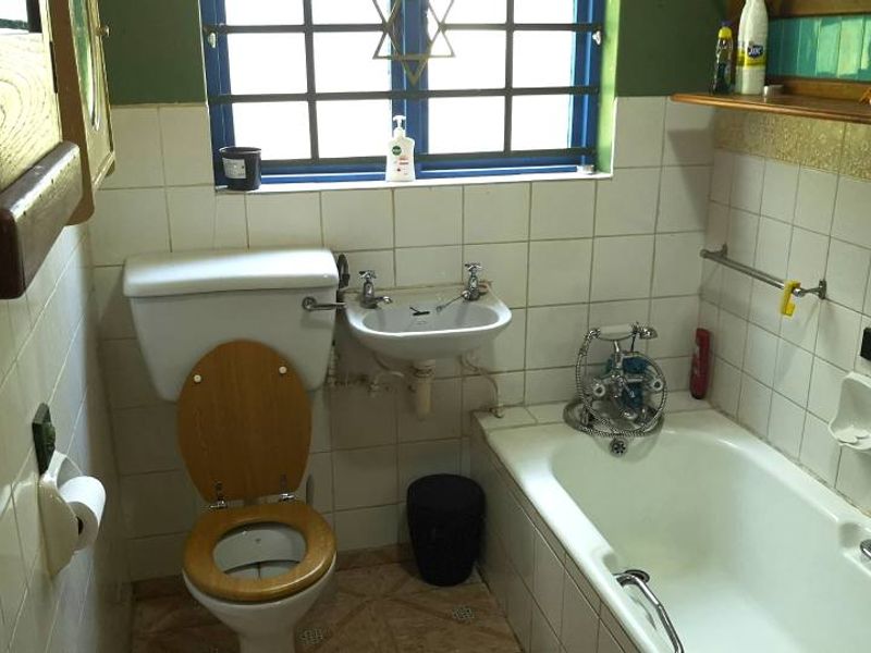 A compact bathroom featuring a standard bathtub, wall-mounted basin, and toilet with dated tiling and finishes.