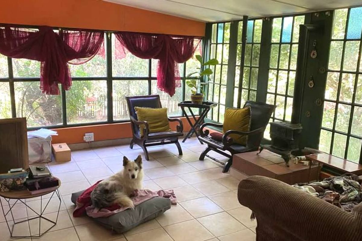 Sunroom featuring extensive glazing, tiled flooring, and a built-in fireplace, offering a bright and versatile living space with garden views.