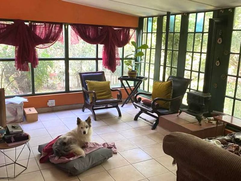 Sunroom featuring extensive glazing, tiled flooring, and a built-in fireplace, offering a bright and versatile living space with garden views.