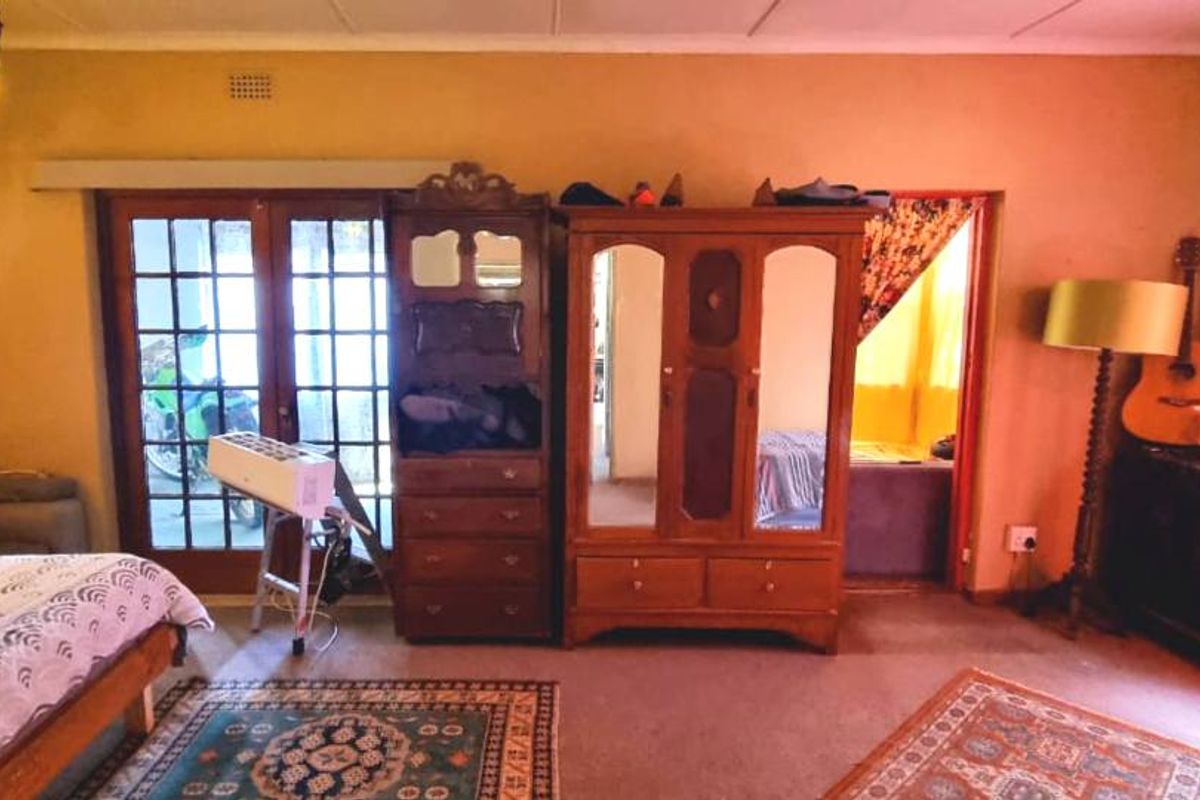 A bedroom featuring carpeted flooring, a ceiling-mounted light fixture, and glass-paned double doors leading to an exterior area.