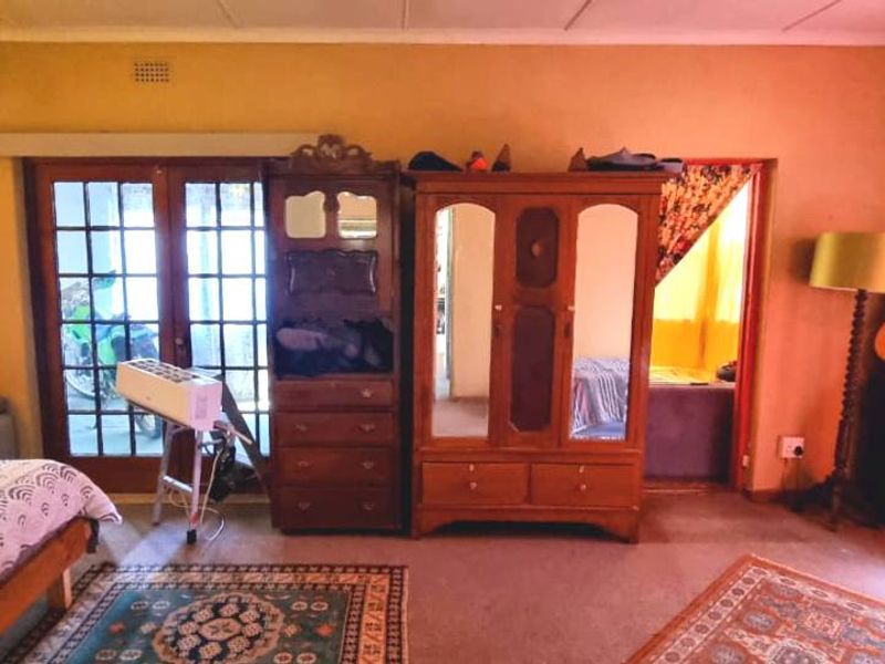 A bedroom featuring carpeted flooring, a ceiling-mounted light fixture, and glass-paned double doors leading to an exterior area.