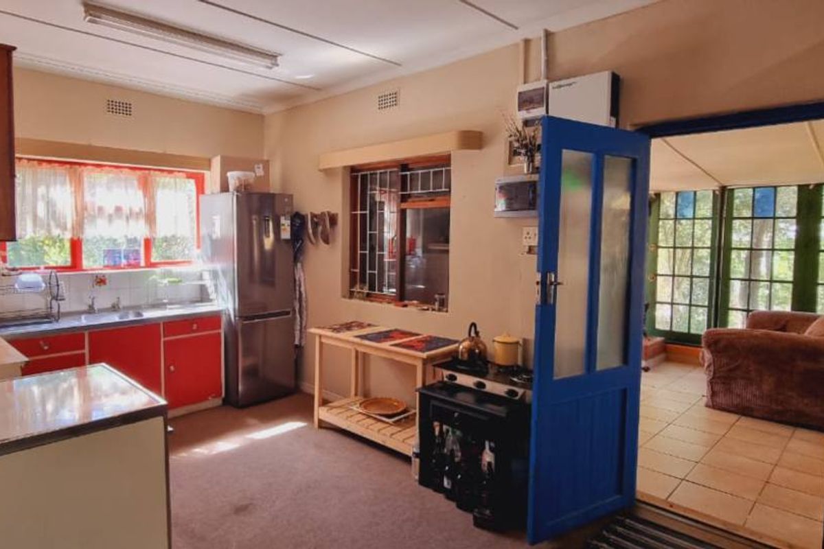 A dated kitchen featuring red cabinetry, a double sink, and direct access to an adjacent sunroom or patio area.