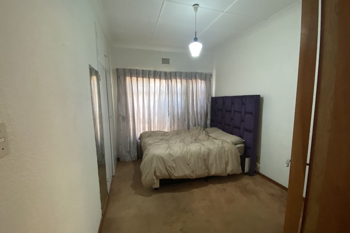 A standard bedroom featuring built-in cupboards, carpeted flooring, and a central pendant light fixture.
