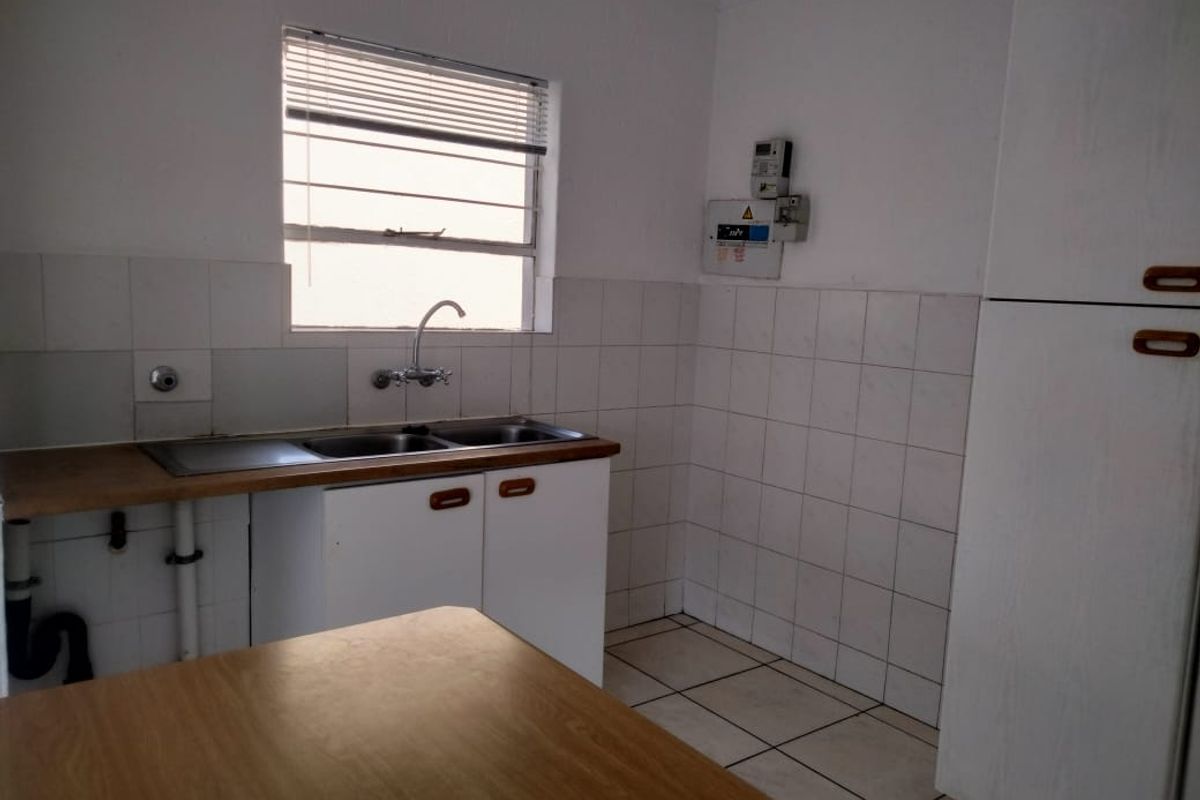 A functional kitchen space featuring a double sink, tiled splashback, and built-in cabinetry, offering a blank canvas for potential renovation and modernization.