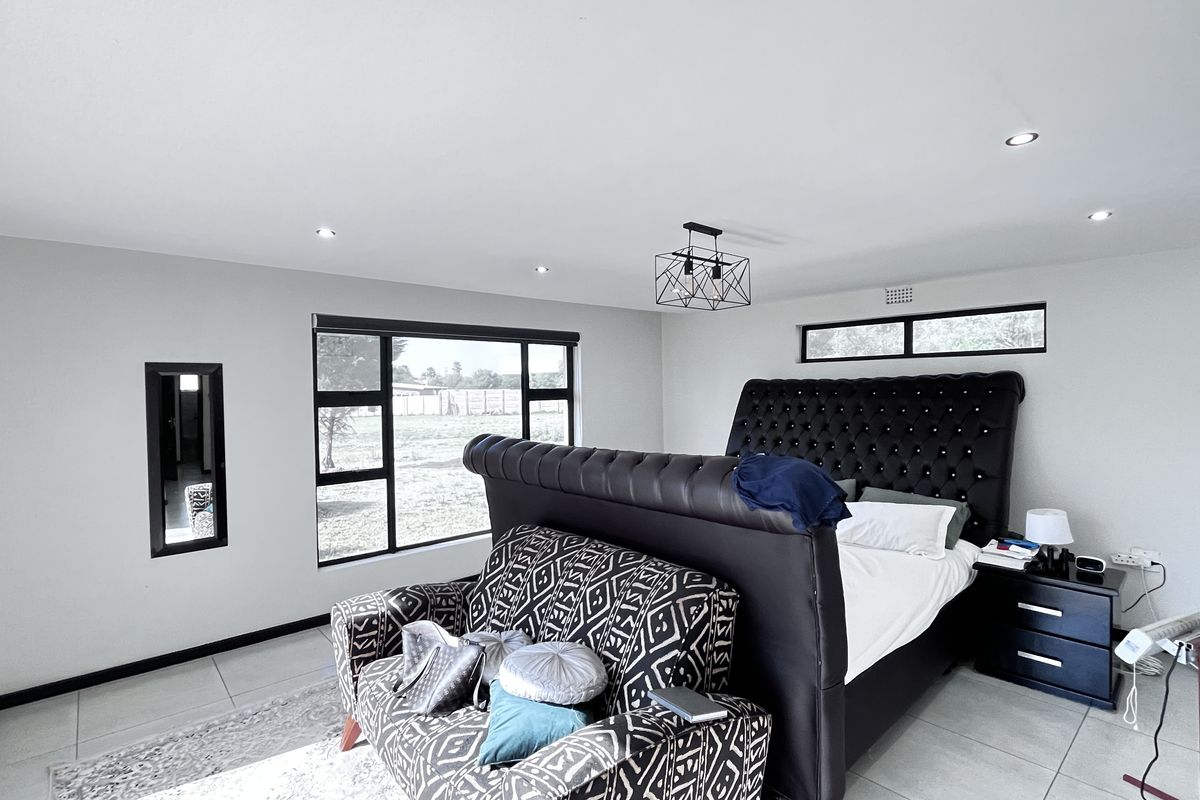 Spacious bedroom featuring modern tiled flooring, recessed downlighting, a contemporary pendant light fixture, and large windows providing ample natural light.
