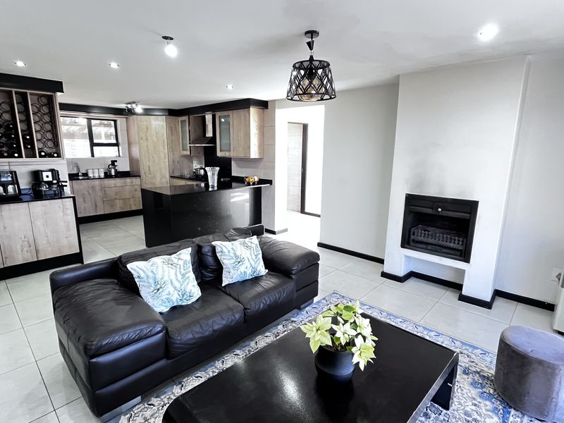 Open-plan living area featuring a modern kitchen with dark countertops, light wood cabinetry, and a built-in fireplace in the lounge section.